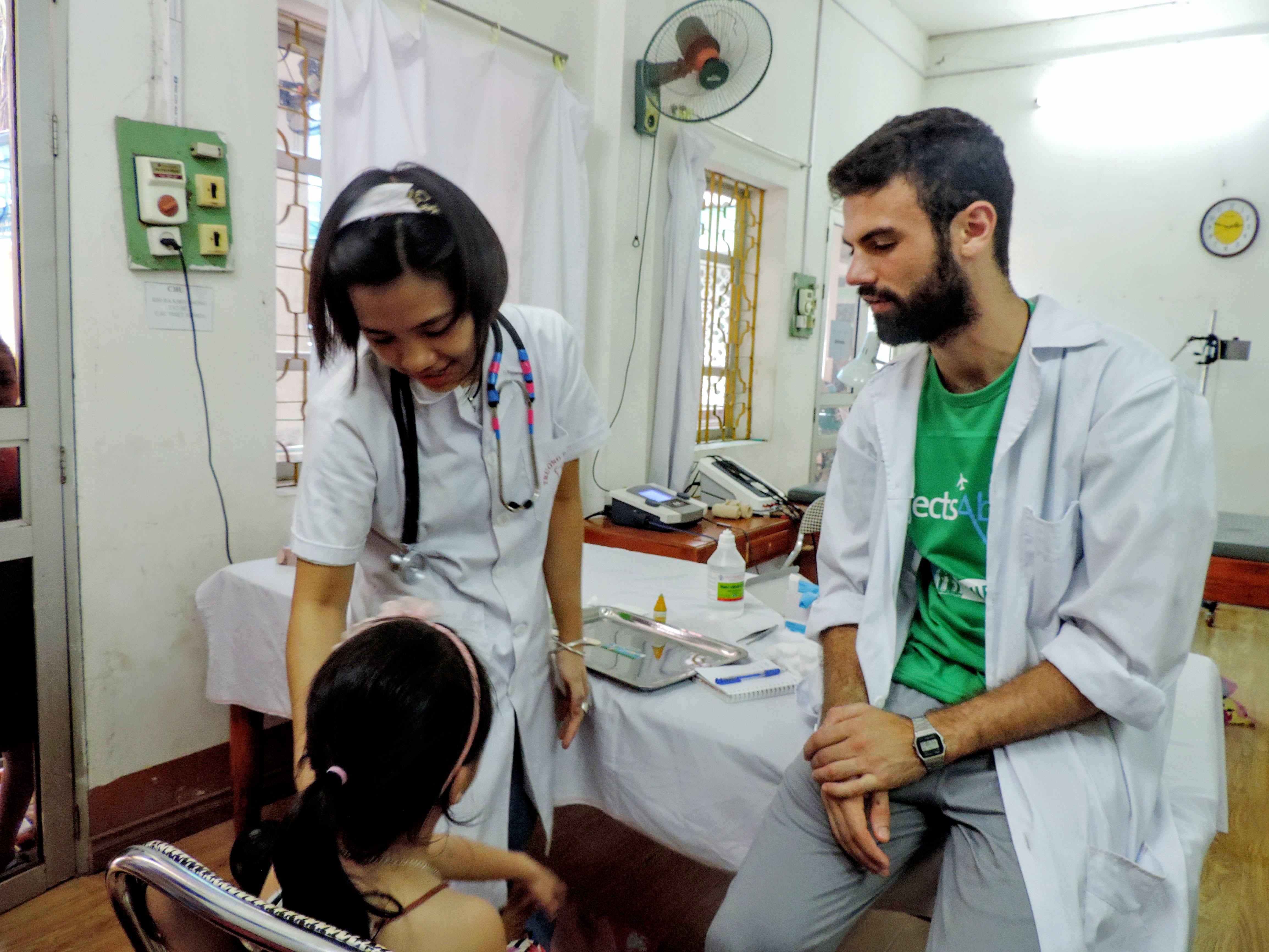 An intern gaining valuable medicine work experience as he assist a local doctor in examining a child during his medical internship in Vietnam with Projects Abroad. A Projects Abroad male intern is seen assisting a local doctor with examining a child whilst he is on his medical internship in Vietnam.